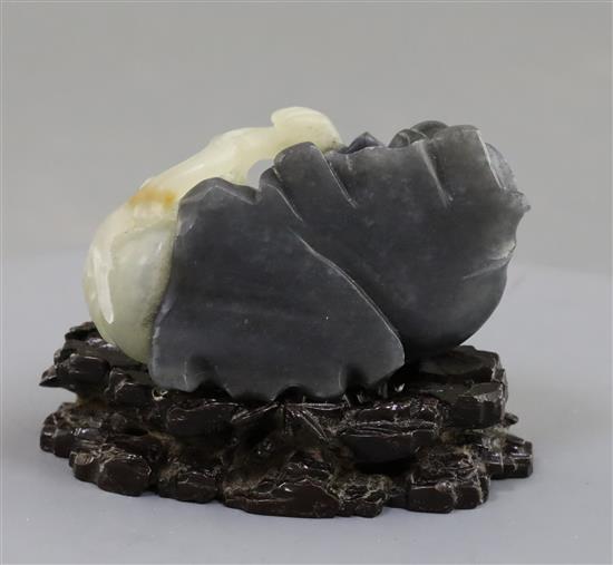 A Chinese pale celadon and grey jade figure of a seated boy, 5.7cm excluding carved wood stand